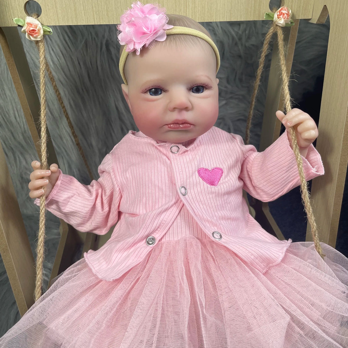 Aria in a pink heart cardigan and flower headband