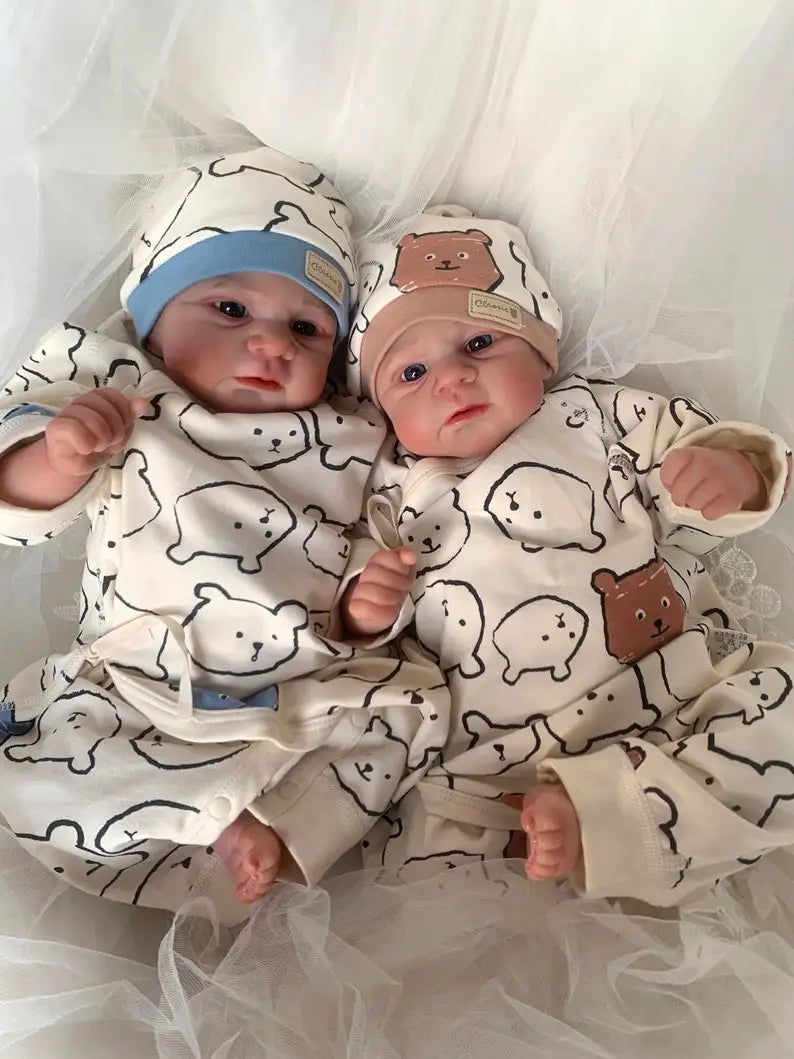 Jude in a blue hat and June in a brown bear hat, lying side by side