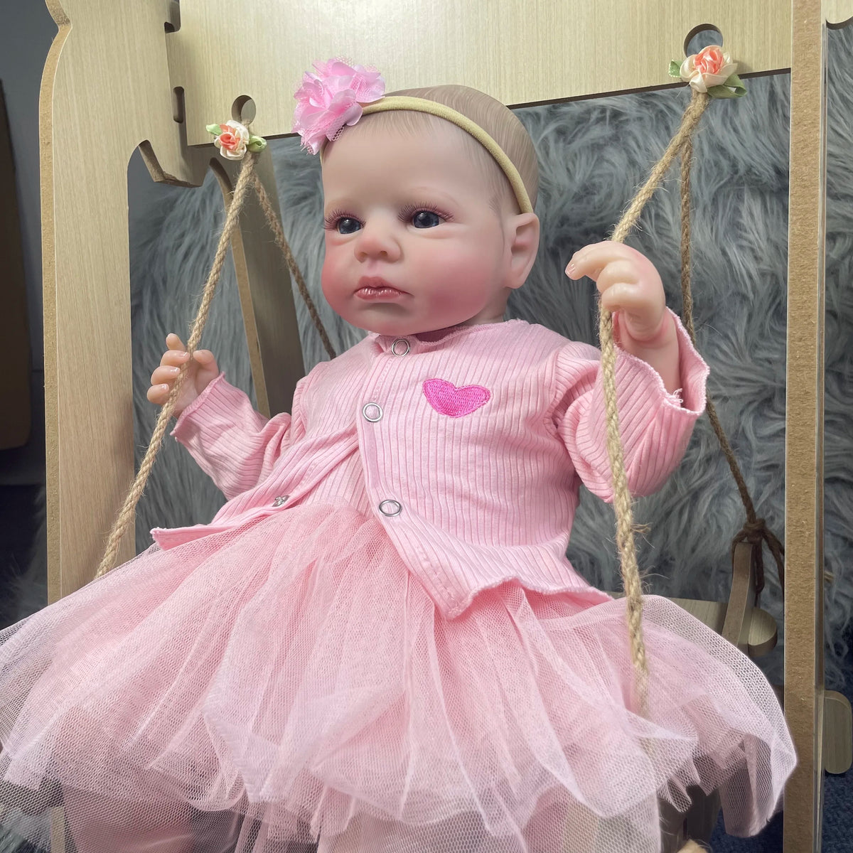 Aria, a 19-inch awake reborn baby girl with blue eyes, in a pink cardigan and tulle skirt