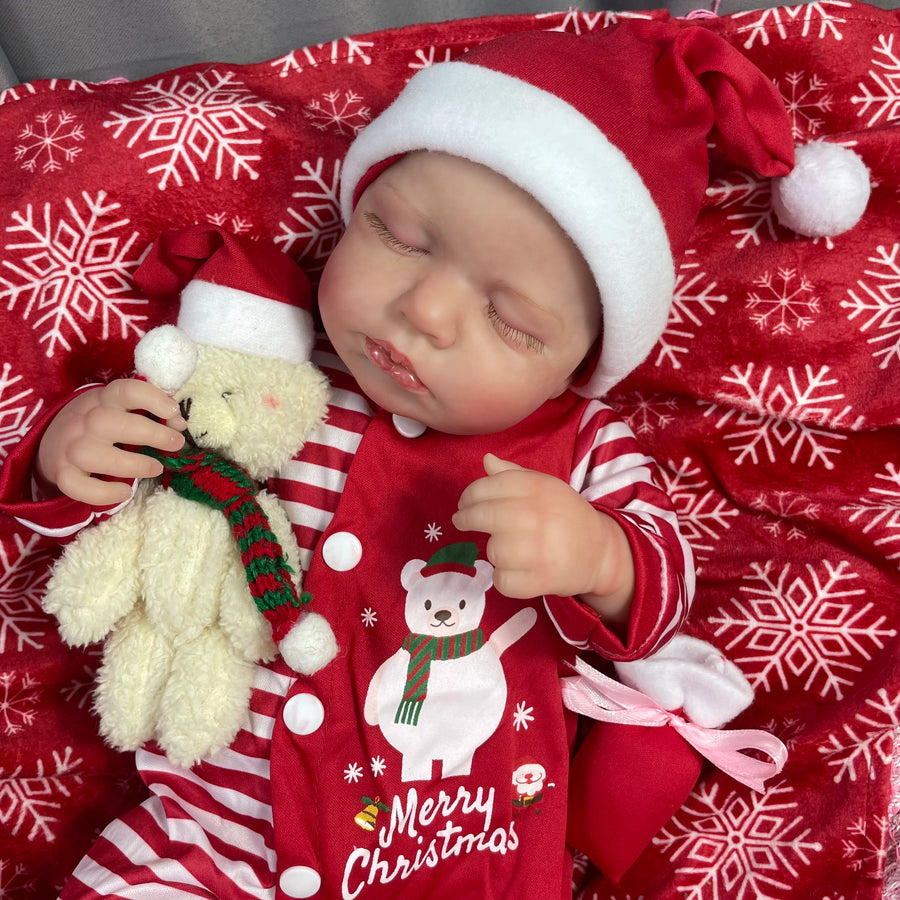Holly, a 20 inch sleeping reborn baby girl in Christmas pajamas and a Santa hat