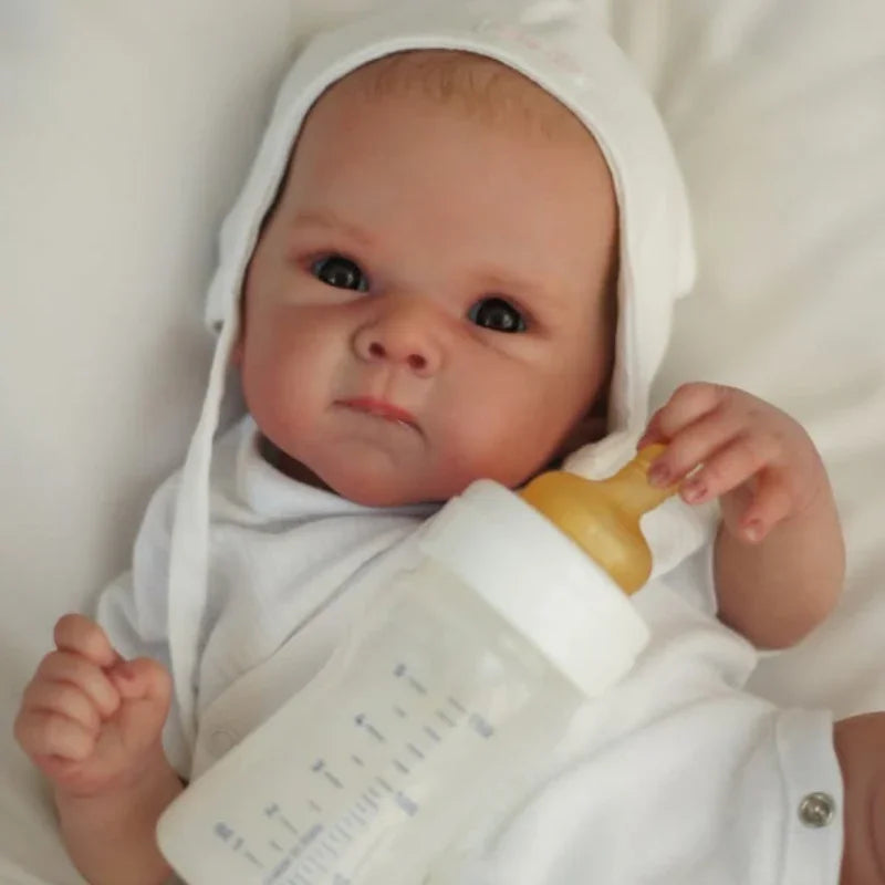 Stella awake in a white bonnet, next to a feeding bottle