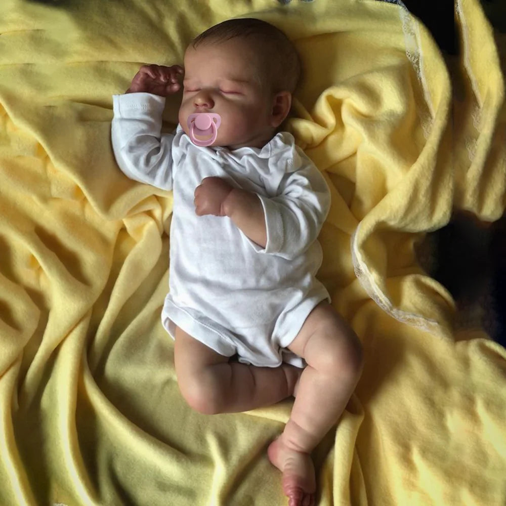 Hallie asleep on a yellow blanket in a white bodysuit