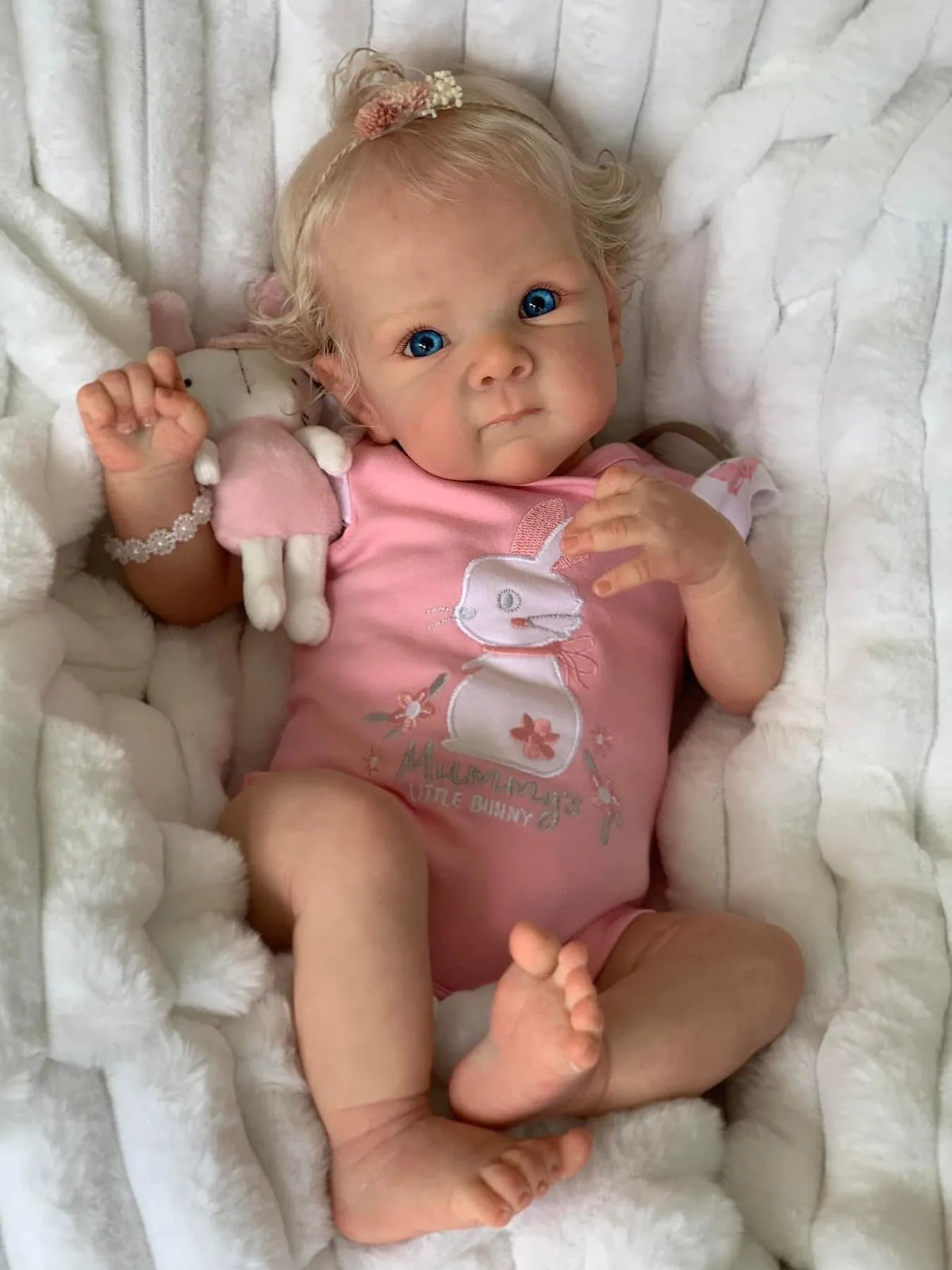Sadie reborn baby girl lying on a white blanket, full length