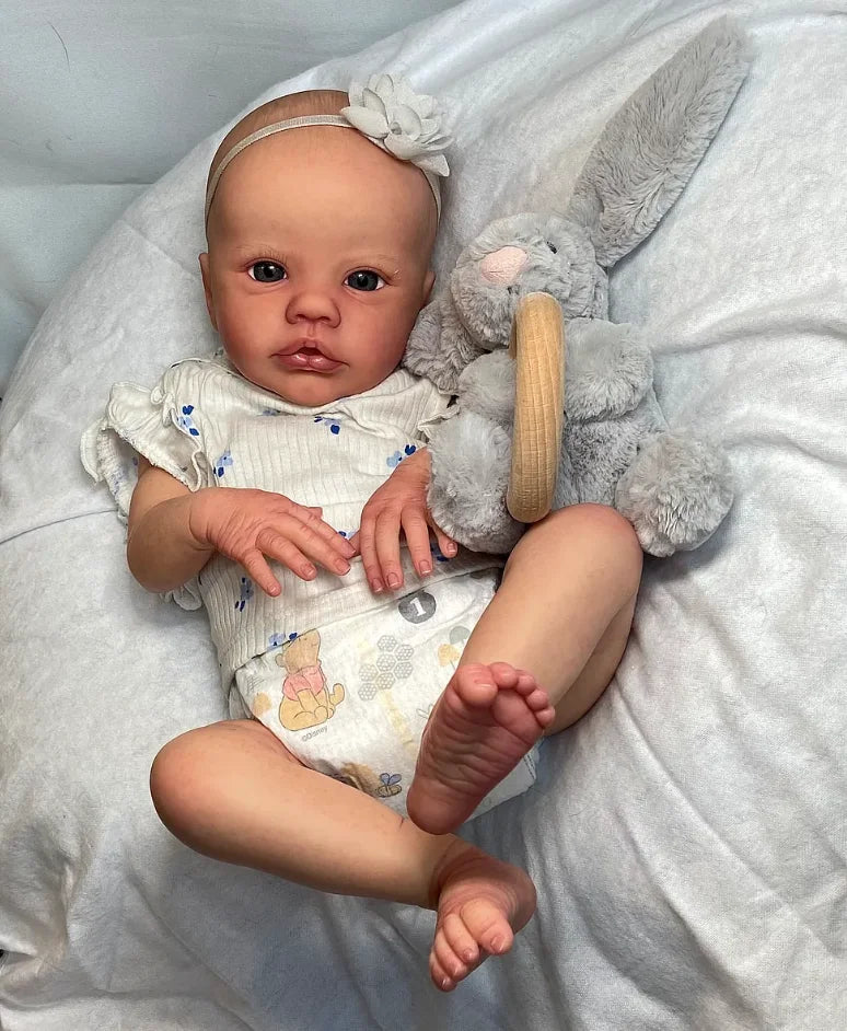 Primrose, a 19-inch awake reborn baby with a soft cloth body, holding a gray bunny toy